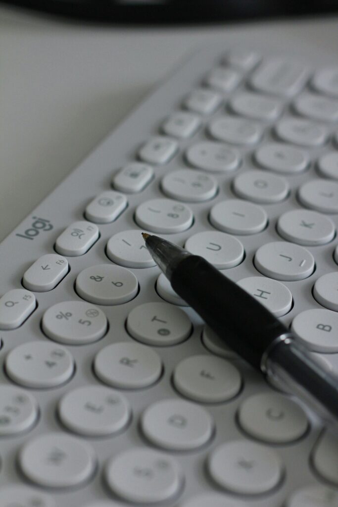 A white circular key keyboard with a black pen, perfect for modern office setups and productivity.